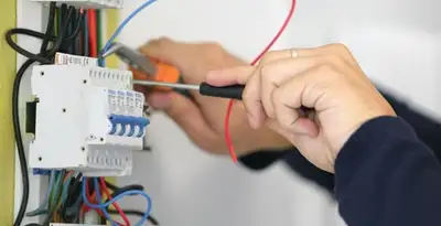 Electrician installing and adjusting circuit breakers in an electrical panel in San Diego, CA