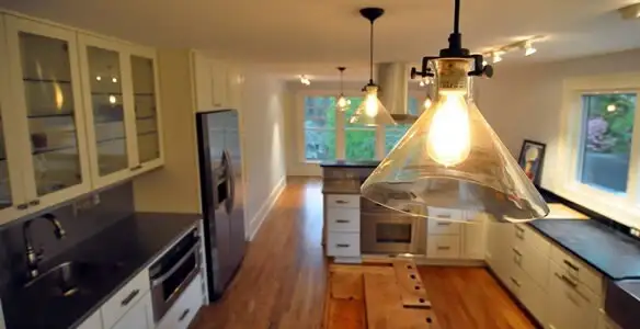 Residential electrician installing modern indoor light fixture in a home in San Diego, CA