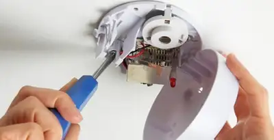 Certified technician wiring smoke detector during installation in San Diego, CA